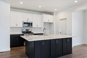 Kitchen featuring sink, wood-type flooring, white cabinetry, and appliances with stainless steel finishes