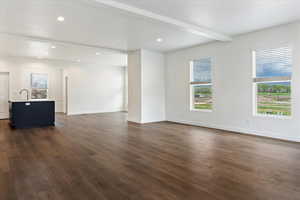 Unfurnished living room with dark hardwood / wood-style flooring and beam ceiling