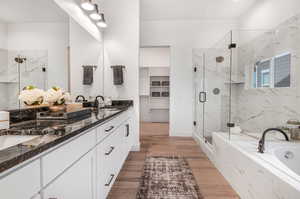 Bathroom with double vanity, shower with separate bathtub, and hardwood / wood-style floors