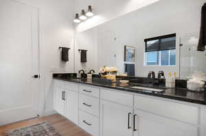 Bathroom with double vanity, walk in shower, and hardwood / wood-style floors