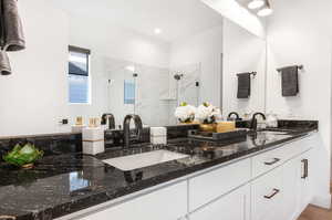 Bathroom featuring wood-type flooring, walk in shower, large vanity, and double sink