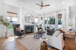 Living room with hardwood / wood-style floors, a tiled fireplace, and ceiling fan