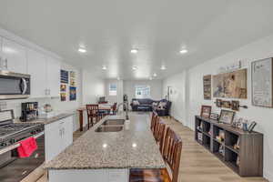 Kitchen featuring appliances with stainless steel finishes, white cabinetry, sink, and a center island with sink