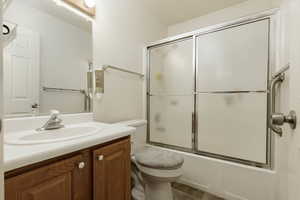 Full bathroom featuring bath / shower combo with glass door, vanity, and toilet