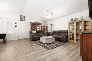 Living room featuring ceiling fan, light hardwood / wood-style flooring, and lofted ceiling