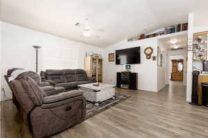 Living room featuring lofted ceiling, wood-type flooring, and ceiling fan