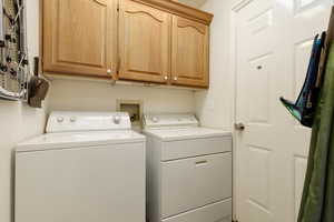 Washroom with cabinets, washer hookup, and washing machine and clothes dryer