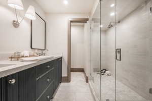 Bathroom with tile floors, a shower with door, and double sink vanity