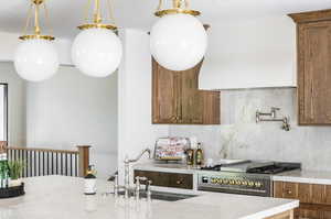 Kitchen with backsplash, sink, light stone counters, and pendant lighting