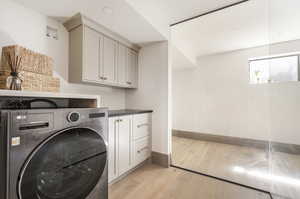 Laundry area featuring cabinets, light wood-type flooring, and washer / clothes dryer