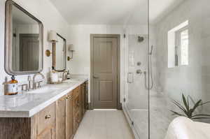 Bathroom featuring tile floors, a shower with door, double sink, and oversized vanity