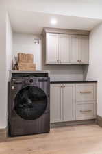 Washroom featuring washer / dryer, cabinets, and light hardwood / wood-style floors