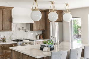 Kitchen with light stone countertops, high end fridge, backsplash, a center island, and gas range