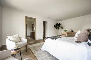 Bedroom with ensuite bath and light wood-type flooring