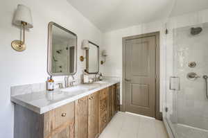 Bathroom featuring tile floors, a shower with door, and double sink vanity