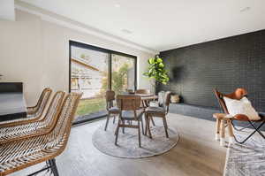 Dining room with brick wall and light wood-type flooring