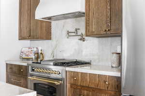 Kitchen featuring appliances with stainless steel finishes, backsplash, and custom exhaust hood