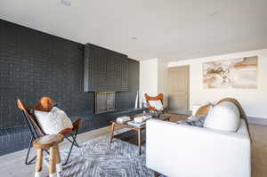 Living room featuring brick wall, a brick fireplace, and light hardwood / wood-style floors