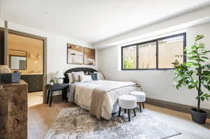 Bedroom with ensuite bathroom, light hardwood / wood-style flooring, and sink