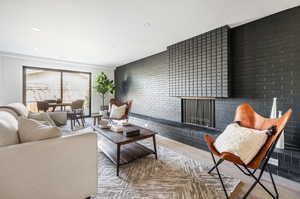 Living room with a fireplace, wood-type flooring, and brick wall