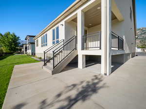 View of property exterior with a lawn and a patio