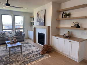 Living room featuring ceiling fan, light hardwood / wood-style floors, and a textured ceiling