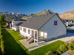 Back of property with a mountain view and a lawn