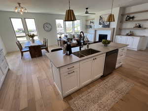 Kitchen featuring white cabinets, sink, dishwasher, light hardwood / wood flooring, and a kitchen island with sink