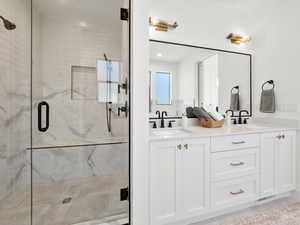 Bathroom featuring dual vanity, a shower with door, and tile patterned floors