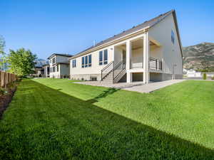 Rear view of property featuring a mountain view and a lawn