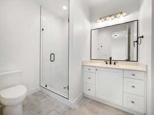 Bathroom with tile patterned flooring, a shower with shower door, vanity, and toilet