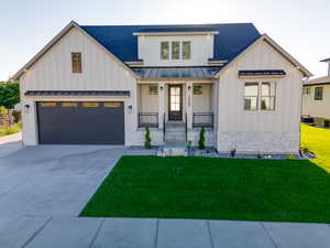 Modern farmhouse featuring a garage and a front lawn full landscape