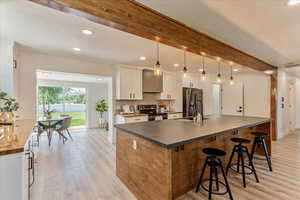 Kitchen featuring stainless steel appliances, hanging light fixtures, white cabinetry, and light hardwood / wood-style flooring