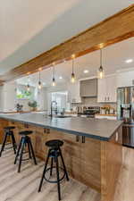 Kitchen with light hardwood / wood-style floors, decorative light fixtures, sink, white cabinetry, and appliances with stainless steel finishes