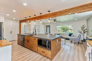 Kitchen featuring ceiling fan, light hardwood / wood-style floors, stainless steel appliances, beam ceiling, and sink