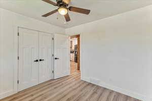 Unfurnished bedroom featuring ceiling fan, a closet, light hardwood / wood-style floors, and stainless steel fridge