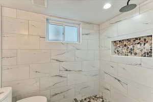 Bathroom featuring a tile shower and toilet