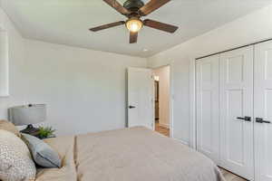 Bedroom with ceiling fan, a closet, and light hardwood / wood-style floors