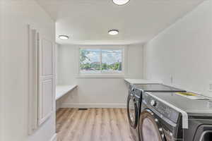 Laundry room with washer and dryer and light hardwood / wood-style floors