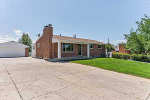 Single story home featuring a front lawn, a garage, an outdoor structure, and central air condition unit