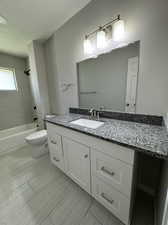 Full bathroom featuring vanity with extensive cabinet space, tile flooring, toilet, and tiled shower / bath combo