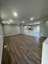 Unfurnished living room featuring sink and dark wood-type flooring