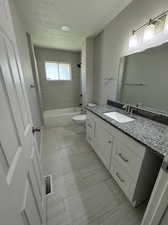 Full bathroom featuring tile floors, tiled shower / bath, vanity, and toilet