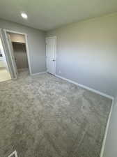 Unfurnished bedroom with carpet, a closet, and a walk in closet