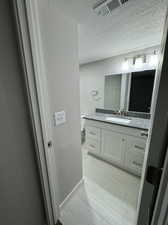 Bathroom with tile floors, a textured ceiling, toilet, and vanity