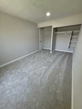 Unfurnished bedroom with a closet, carpet floors, and a textured ceiling