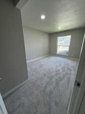 Empty room with a textured ceiling and carpet floors