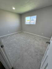 Carpeted empty room featuring a textured ceiling