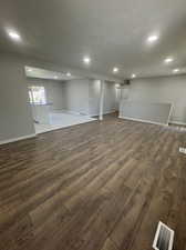 Basement with dark wood-type flooring, sink, and a textured ceiling