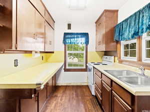 Kitchen with white electric range oven, sink, and hardwood / wood-style flooring